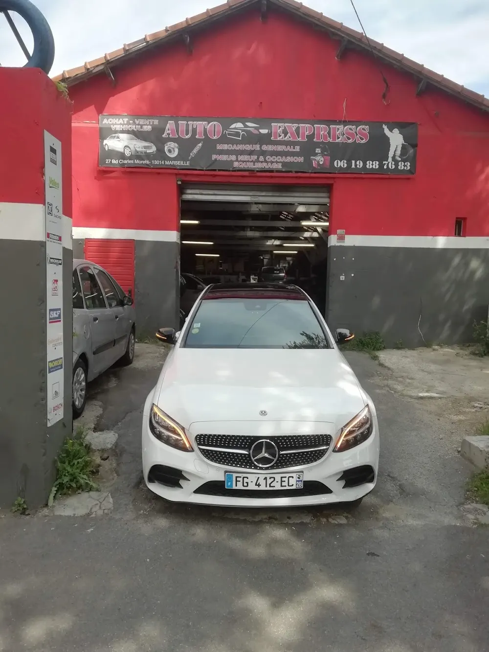 Voiture garée devant la façade rouge du garage Auto Express, boulevard Charles Moretti